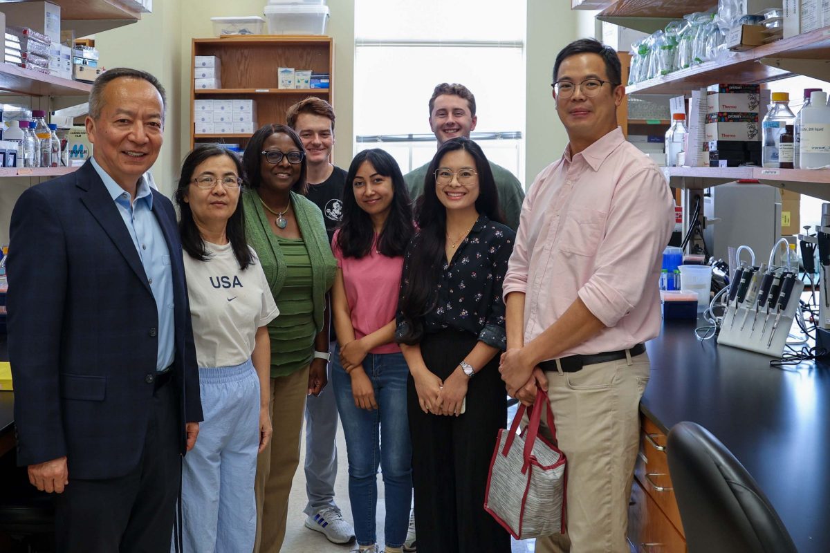 Eight people pose for a group photo in a research laboratory.
