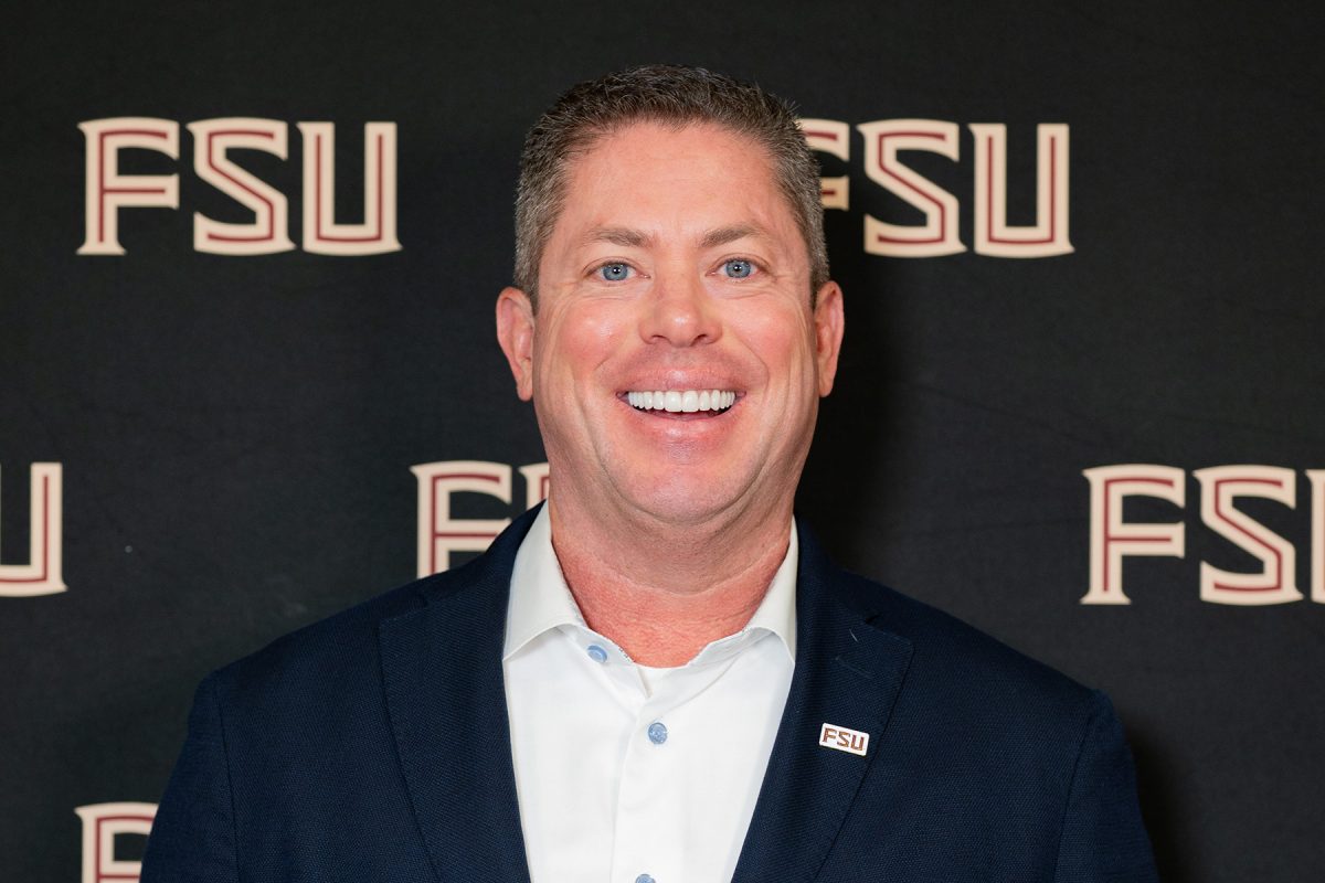 Scott Price standing in front of a black background with FSU logos.