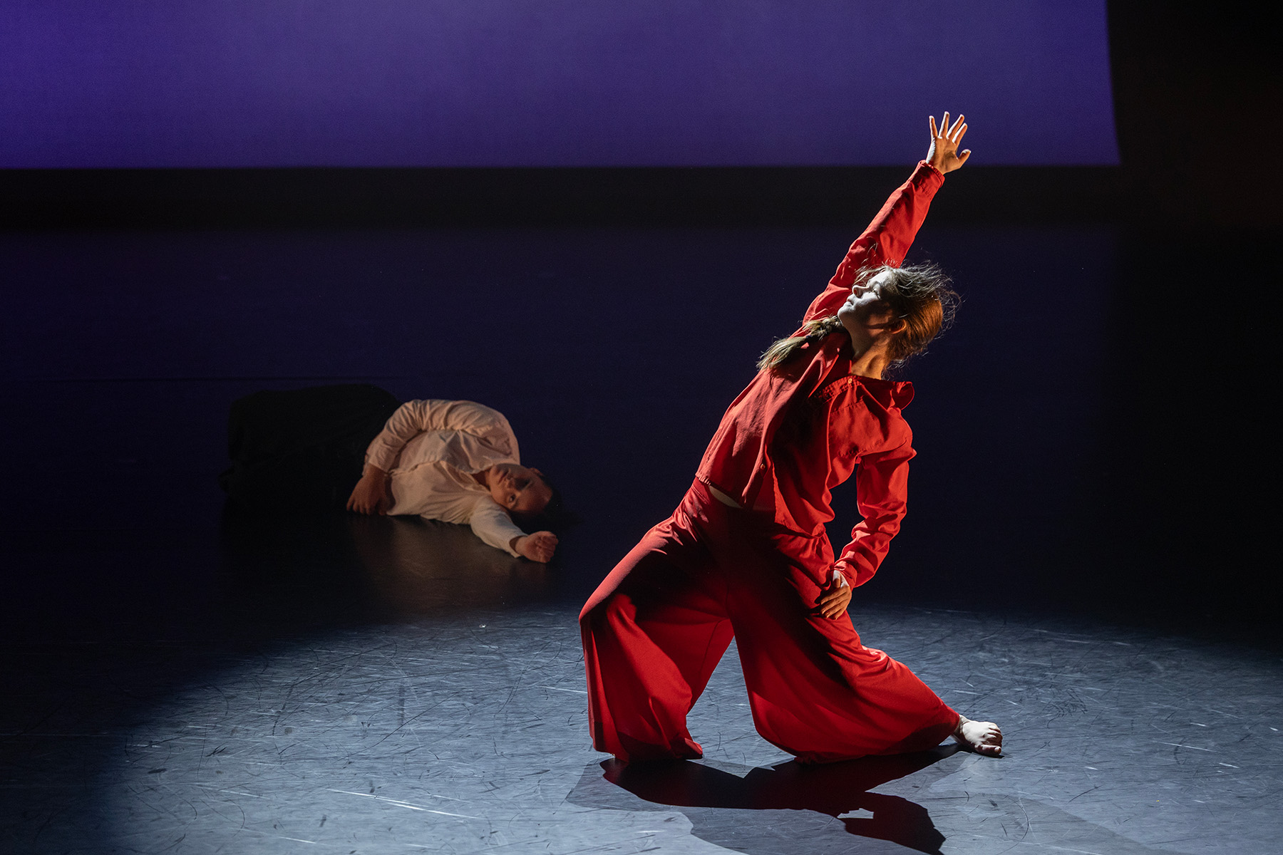 An FSU School of Dance student dressed in red extends one arm overhead while performing onstage during the 2026