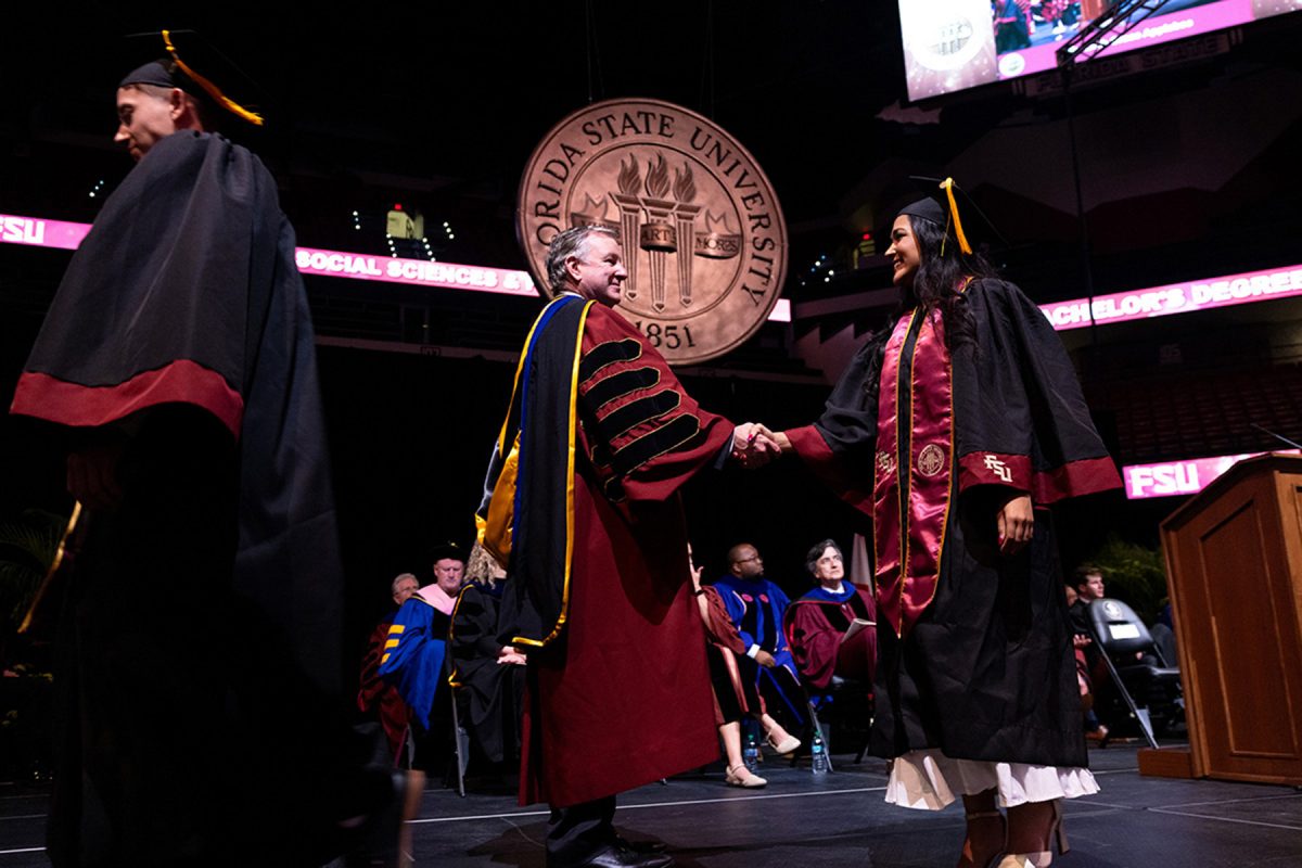 FSU President Richard McCullough shakes hands with a graduate onstage during a commencement ceremony.