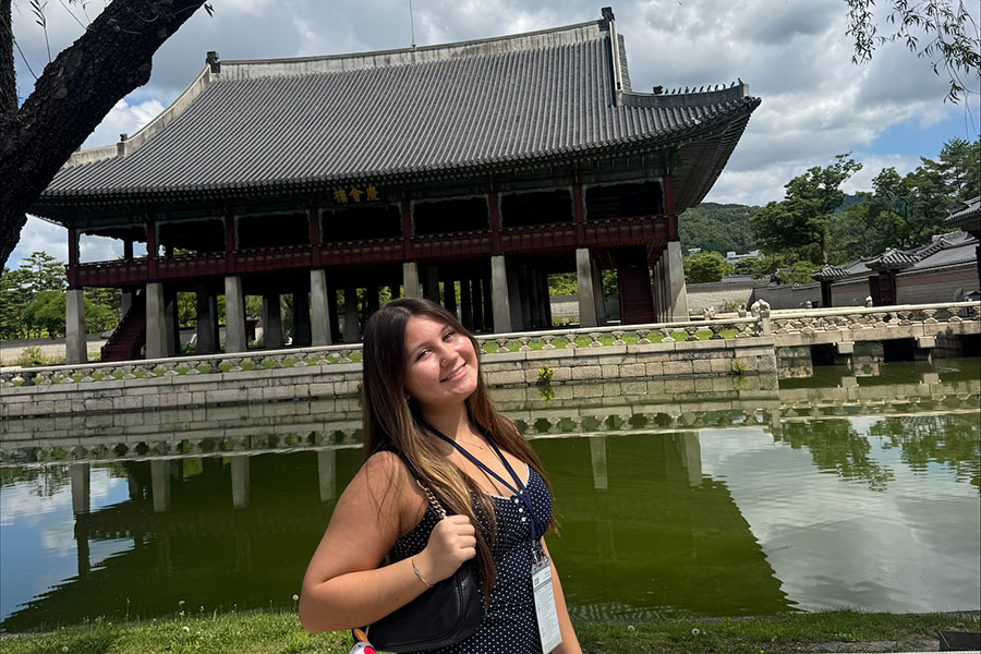 A young woman poses for a photo outside of Gyeonghoeru Pavilion at Gyeongbokgung Palace in Seoul, South Korea.