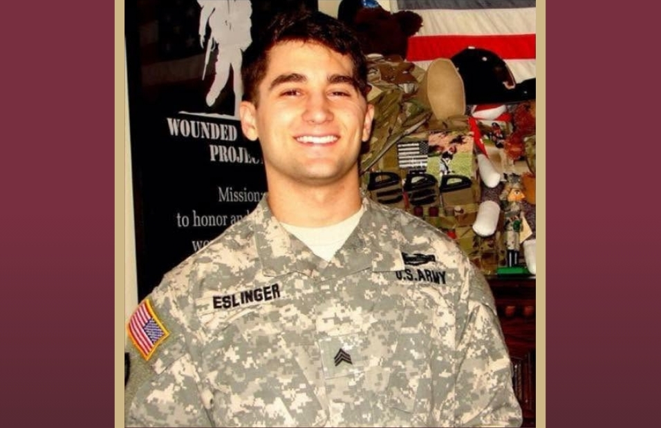 A smiling US Army soldier in a camouflage uniform with the name tape "ESLINGER."
