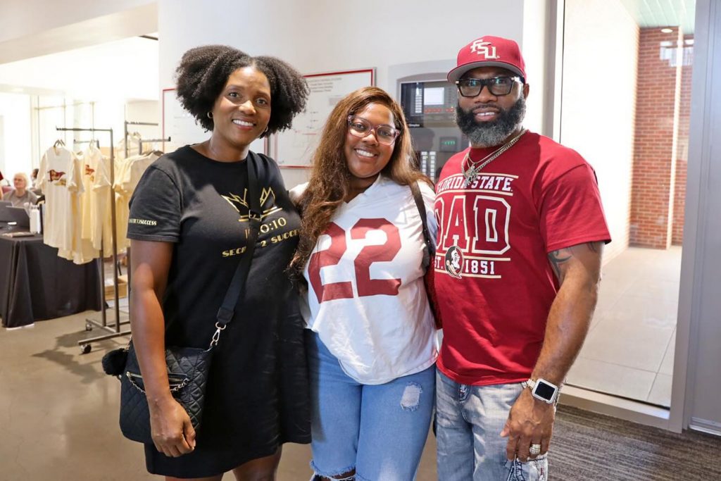 A student smiles for a group photo with her parents.
