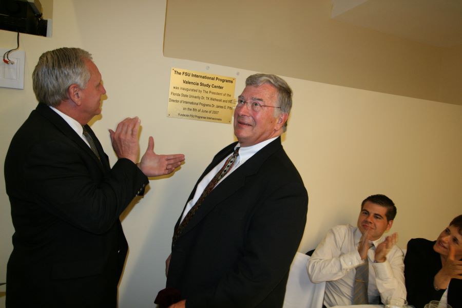 Two men clapping as one looks to the side off camera.