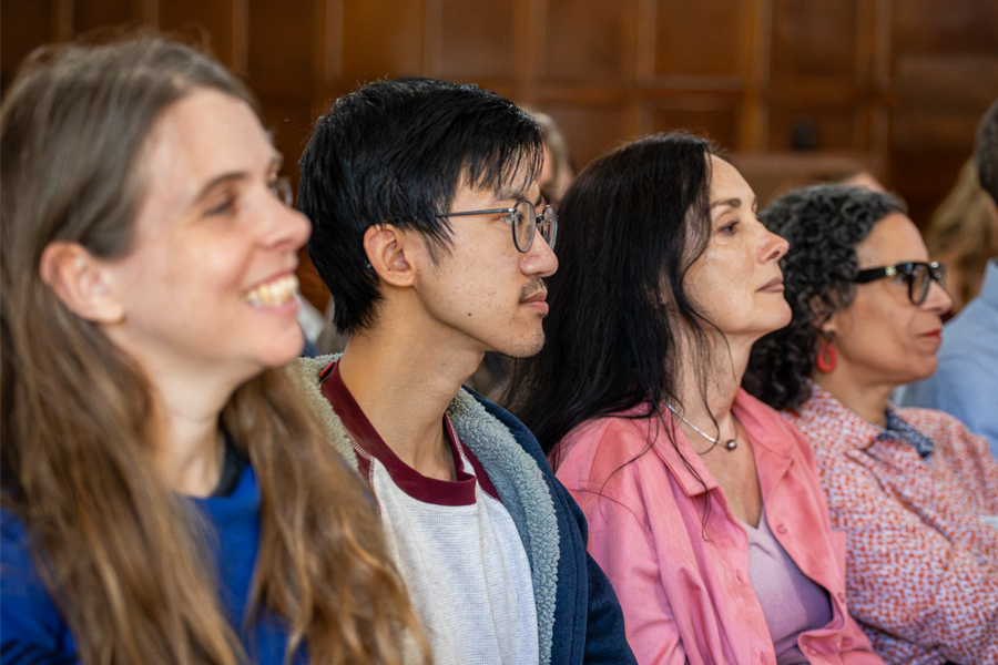 The faces of several people sitting in an audience.