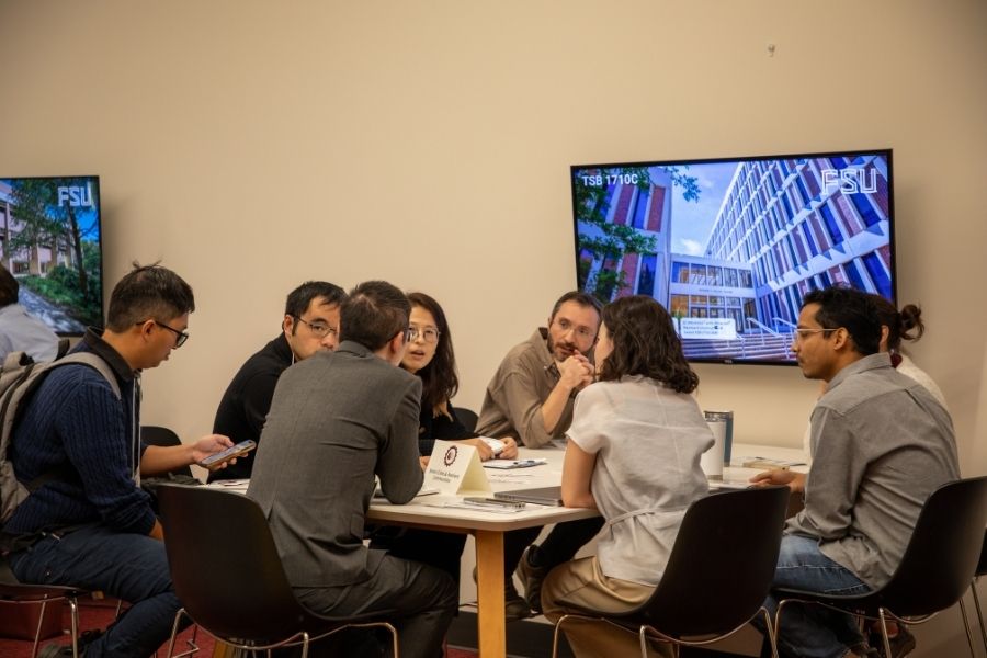 Participants gather around a table for a small-group discussion during FSU’s Collaborative Collision event on artificial intelligence and interdisciplinary research.