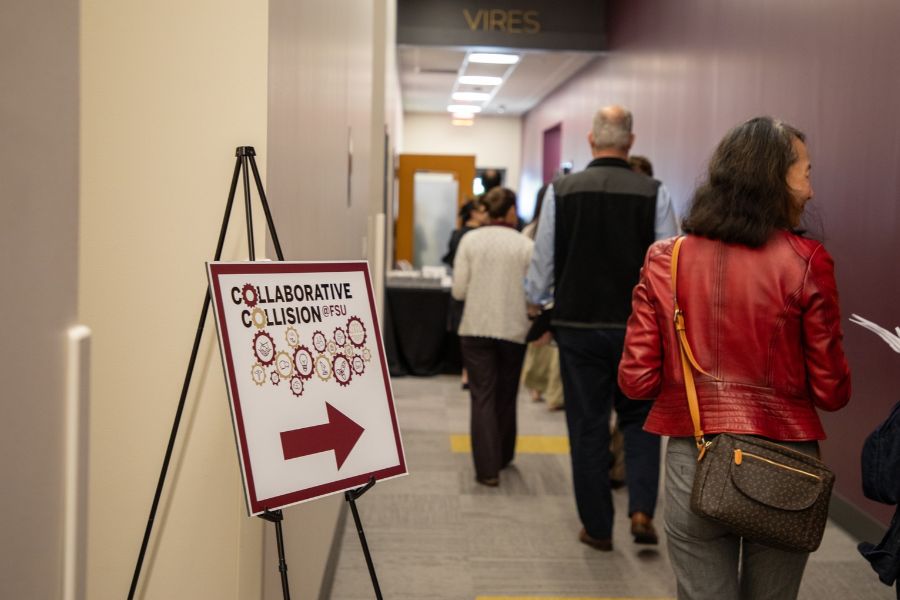 A “Collaborative Collision @ FSU” directional sign points attendees toward the event as participants walk through a hallway.