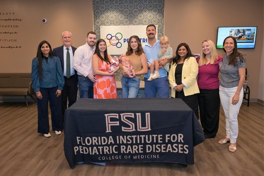 A group photo of several people in behind a tablecloth reading "FSU, Florida Institute for Pediatric Rare Diseases, College of Medicine"