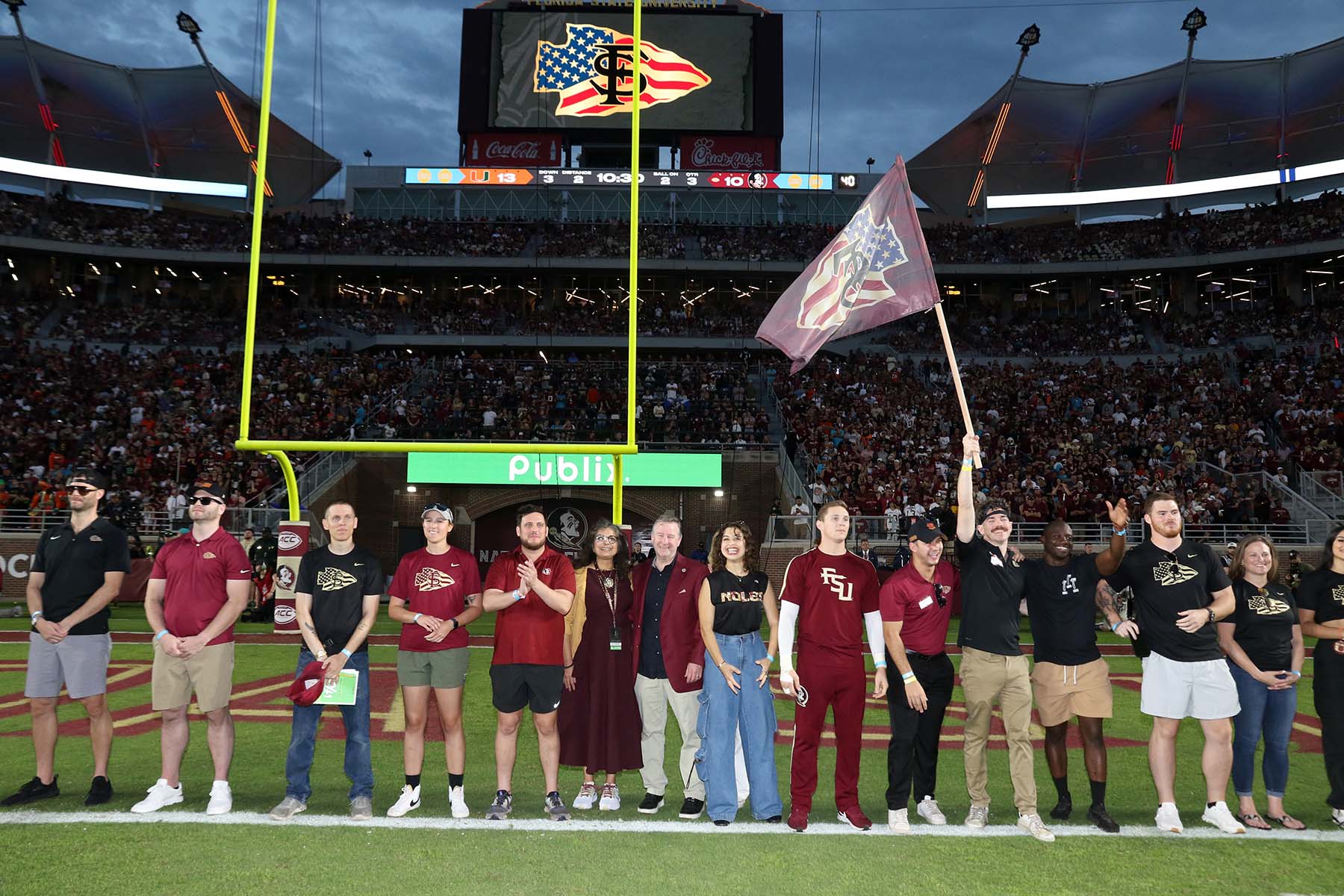 A group of veterans pose on Bobby Bowden Field in Doak S. Campbell Stadium with FSU President Richard McCullough and First Lady Jai Vartikar.