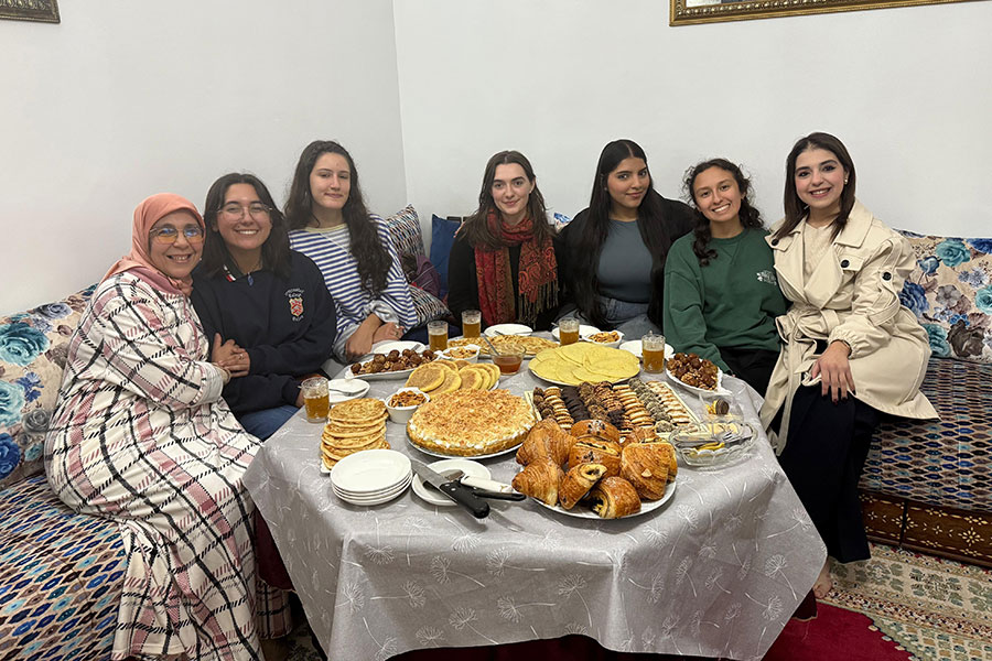 Seven people sitting around a spread of assorted Moroccan food.