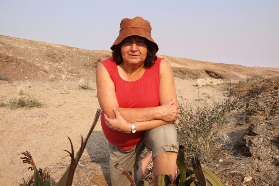 A woman kneeling on one knee in a desert landscape.