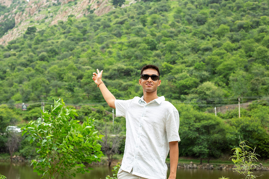 A young man points toward the Aravalli Range in India.