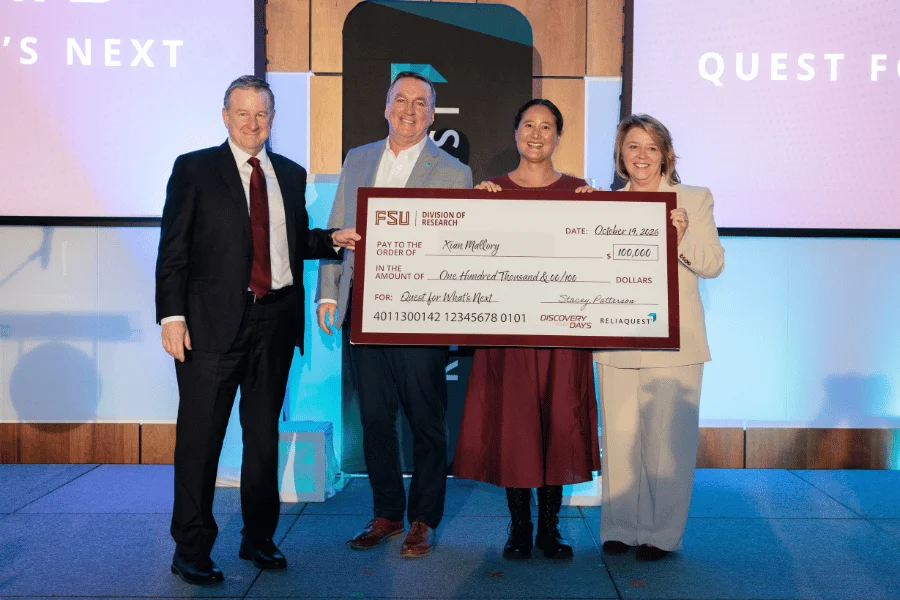 Four people on a stage holding a large $100,000 ceremonial check for an FSU cybersecurity prize.